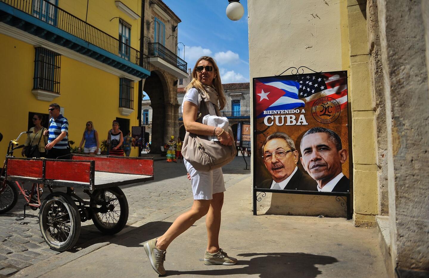 A tourist walks next to a poster of Cuban president Raul Castro and U.S. President Barack Obama on March 17, 2016. Hundreds of workers have been scrambling for days to touch up building facades, patch potholes and spiff up Havana's monuments ahead of Obama's visit.