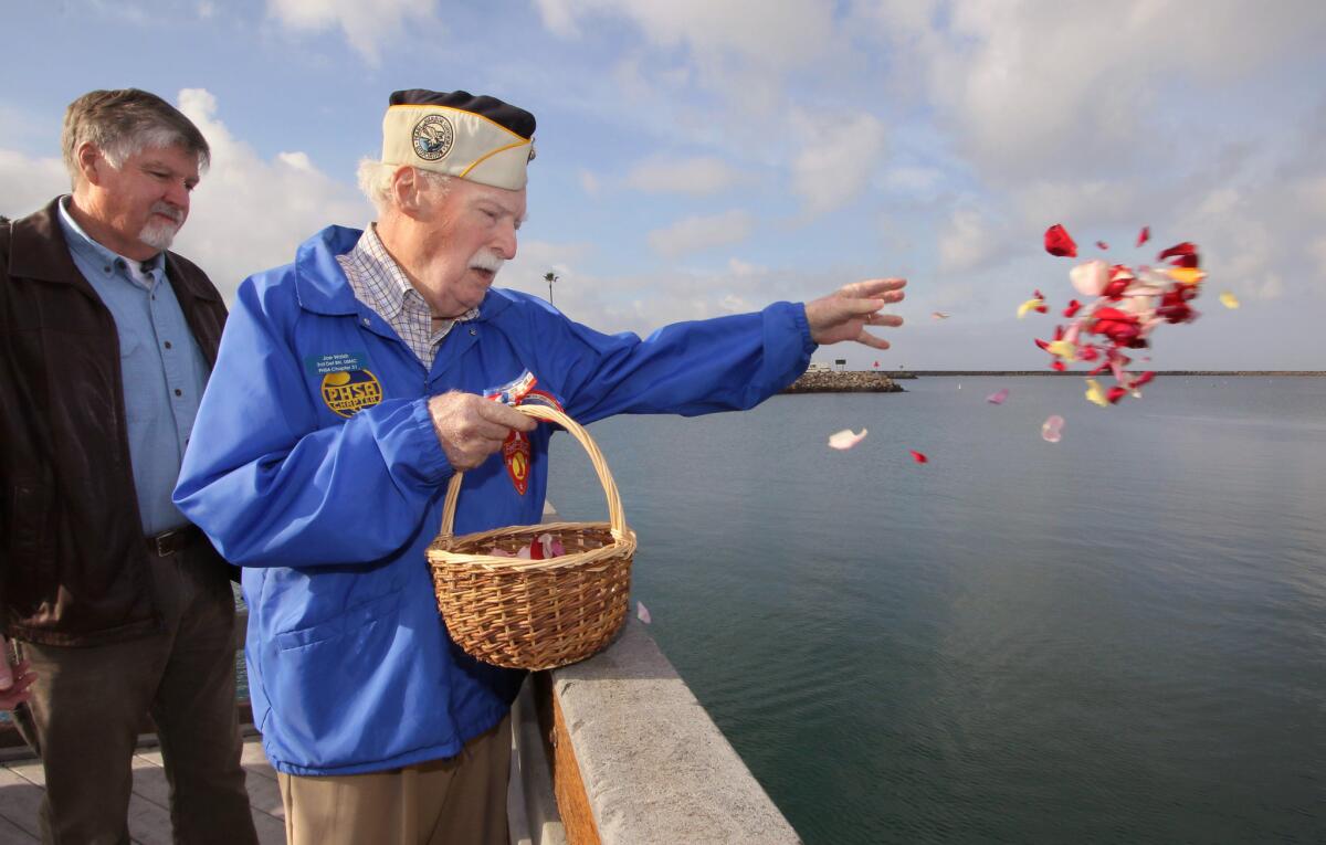 Pearl Harbor survivor Joe Walsh, with son Thomas Walsh, tosses petals in the water during a 2016 Pearl Harbor memorial event in Oceanside.