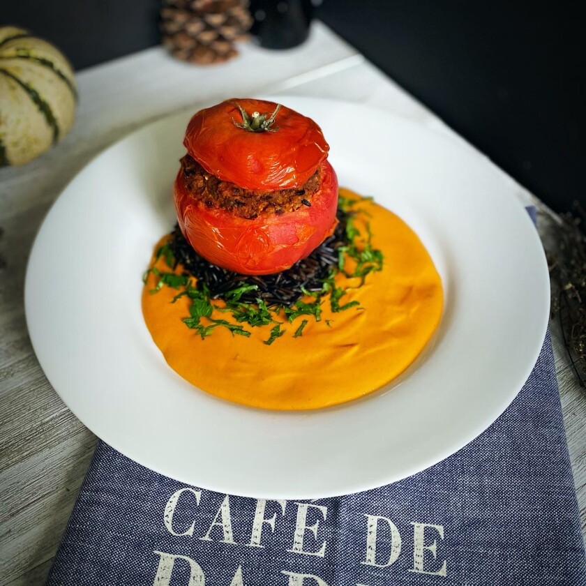 Stuffed tomato served on a bed of wild rice with tomato bisque and fresh parsley.