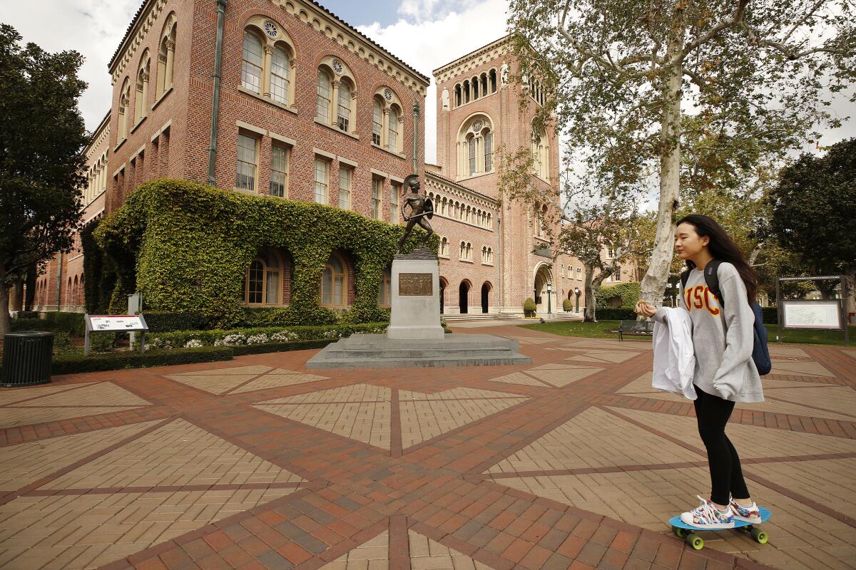 A student rides a penny skateboard across the USC campus.