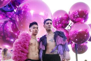Two people pose for a fashion portrait in front of a sculpture of pink globes 