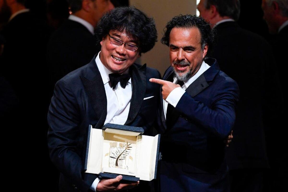 South Korean director Bong Joon-ho poses on stage with Mexican director and president of the Cannes Film Festival jury Alejandro G. Iñárritu after Bong was awarded the Palme d'Or for his film "Parasite."