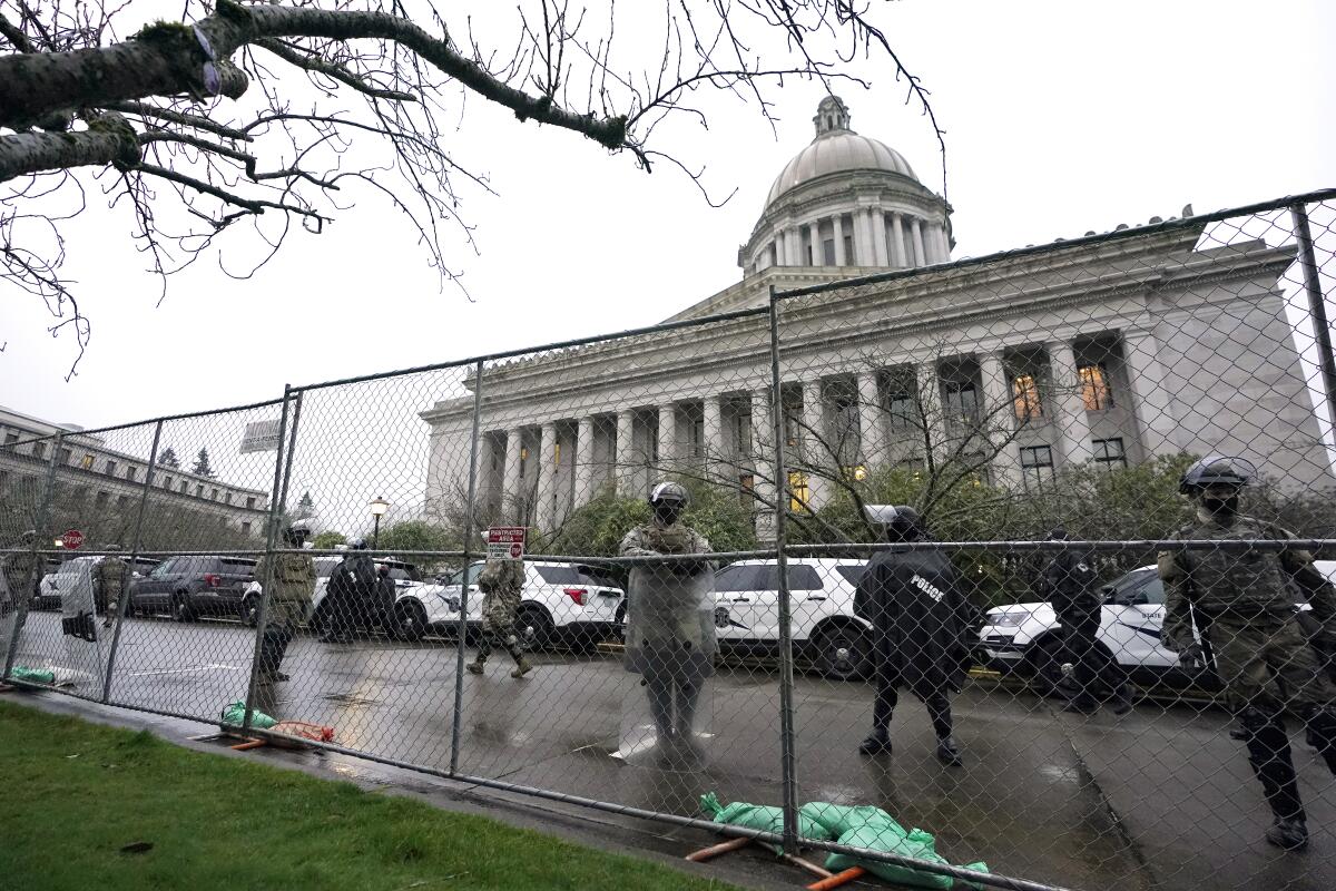 Washington National Guard members stand near a fence surrounding the Capitol in Olympia in anticipation of protests Monday.