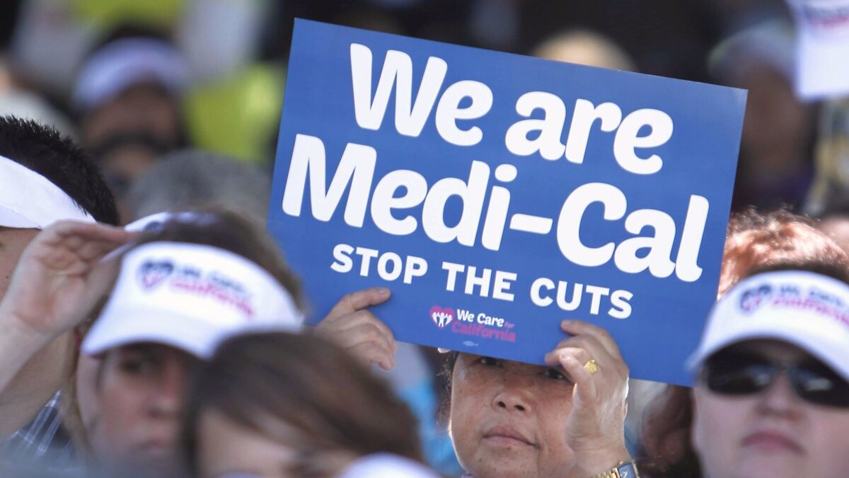Sign-carrying demonstrators representing doctors, hospitals and unionized healthcare workers rally against cuts in the amount the state pays for Medi-Cal reimbursements at the Capitol in Sacramento.