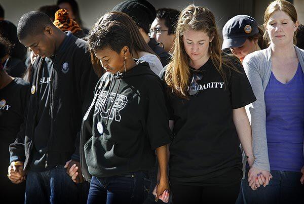 Students clasp hands during a prayer at an emotional but peaceful rally at UC San Diego.