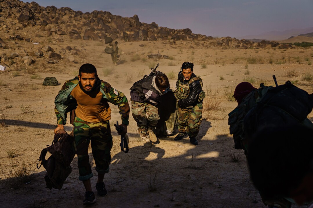 Soldiers dragging a sleeping bag with their belongings down a hill from an outpost in the Shah Wali Kot district,