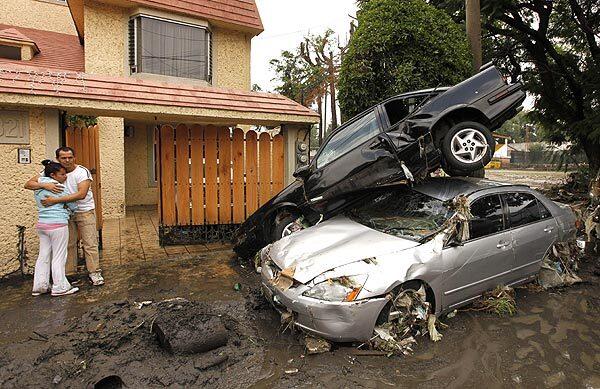 A couple embraces next to cars piled up by floods in Tlanepantla, Mexico.