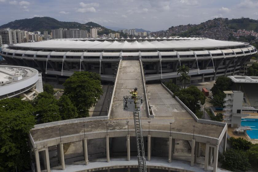 ARCHIVO - En esta foto de archivo del 5 de abril de 2020, un bombero toca una trompeta desde lo más alto de una escalera, frente al estadio de Maracaná en Río de Janeiro, en medio del confinamiento para evitar la propagación del coronavirus (AP Foto/Leo Correa, archivo)
