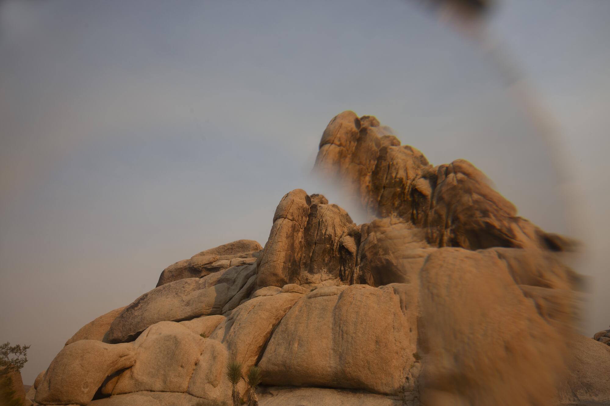 A brown rock formation peeks out of fog.