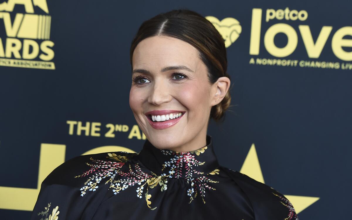 Mandy Moore smiles in an up-do and a high-necked black dress with sparkling floral accents
