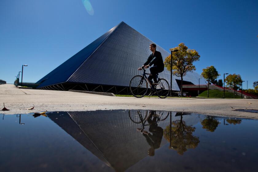 Long Beach, CA., March 11, 2020 - A student bikes pass The Walter Pyramid at Cal State Long Beach, where the campus has gone to online only classes on Tuesday, March 11, 2020 in Long Beach, California. (Jason Armond / Los Angeles Times)