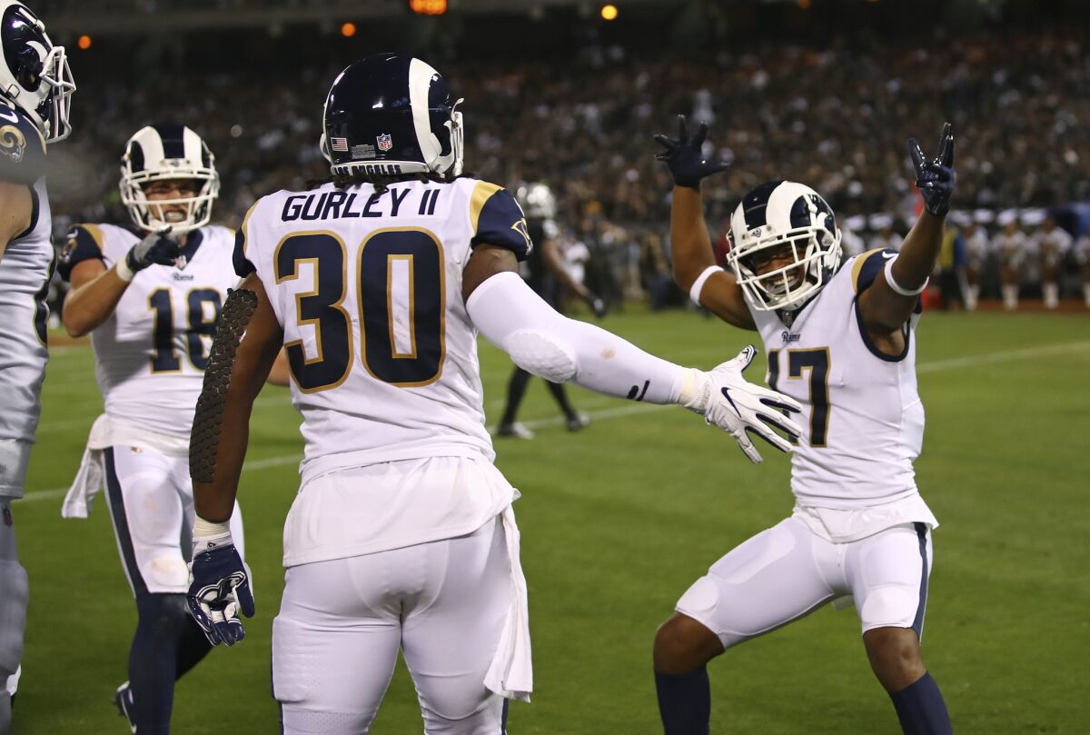 Los Angeles Rams running back Todd Gurley is greeted by teammates Cooper Kupp (18) and Robert Woods (17) after scoring a touchdown during the first half.