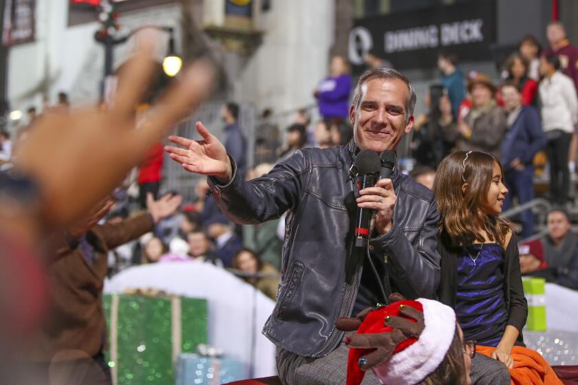 Hollywood, CA - November 27: A person gives outgoing Los Angeles Mayor Eric Garcetti, shown with daughter, Maya Juanita Garcetti, the peace sign while riding in The 90th anniversary Hollywood Christmas Parade in Hollywood Sunday, Nov. 27, 2022. (Allen J. Schaben / Los Angeles Times) Actor Danny Trejo served as grand marshal of the parade, which will also feature dozens of movie and TV stars and other celebrities, movie and novelty cars, balloons, marching bands and city officials. Parade hosts include Erik Estrada, Laura McKenzie, Dean Cain, Montel Williams, special co-host Elizabeth Stanton.