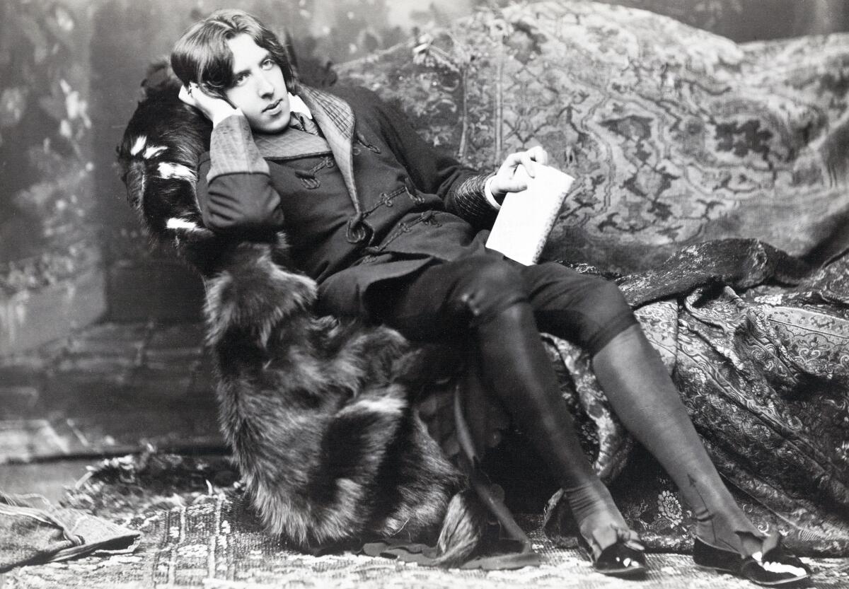 Vintage photo of poet and novelist Oscar Wilde sitting in a fur-lined chair surrounded by rugs