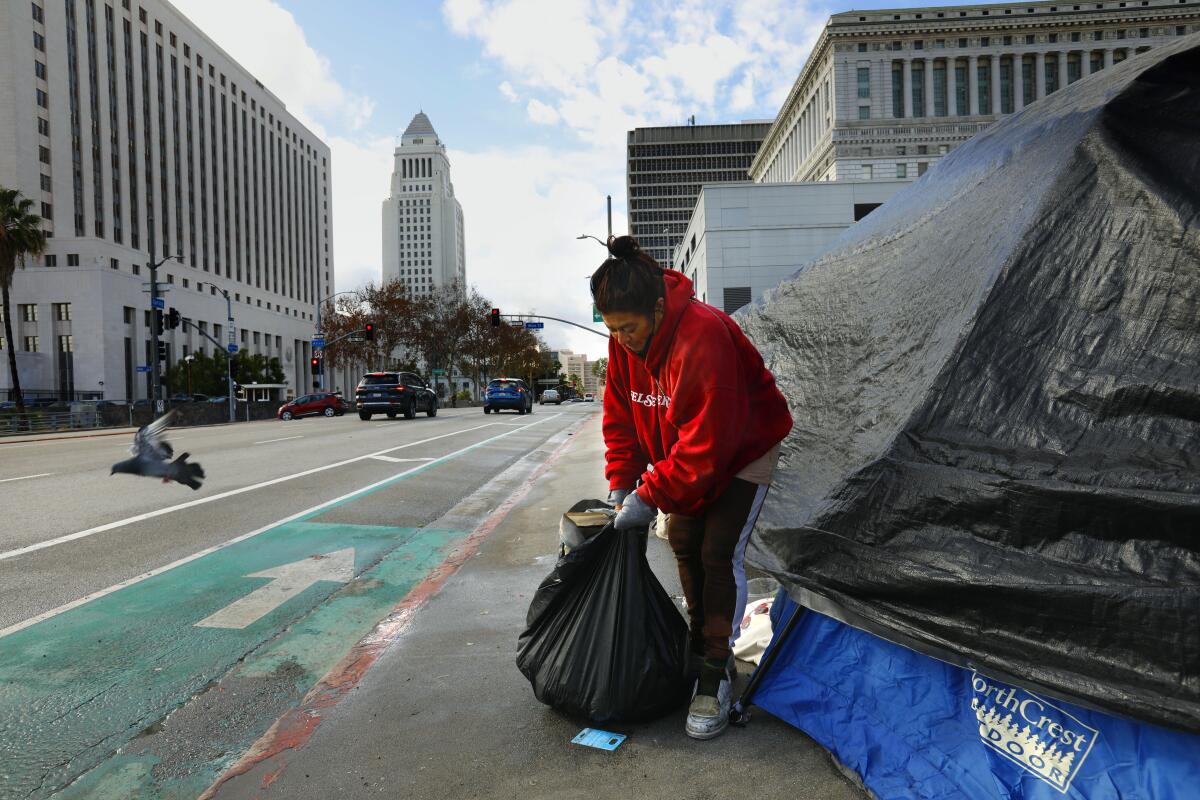 A woman cleans up her camping area on Spring Street, one block from Los Angeles City Hall.