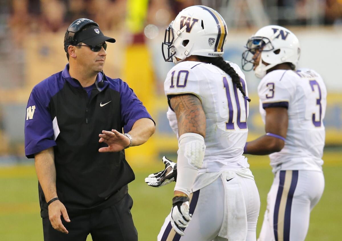 Washington Coach Steve Sarkisian, left, congratulates players John Timu, center, and Cleveland Wallace during a loss to Arizona State on Oct. 19.