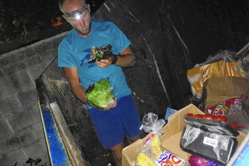 Activist Rob Greenfield inspects the contents of a dumpster near Cleveland, looking for food to put on display for the pubilc in an attempt to raise awareness about how much food is wasted every day.