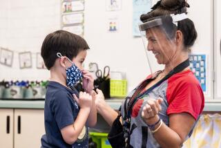 FILE - In this Aug. 12, 2021, file photo, a student gets help with his mask from transitional kindergarten teacher Annette Cuccarese during the first day of classes at Tustin Ranch Elementary School in Tustin, Calif. Now that California schools have welcomed students back to in-person learning, they face a new challenge: A shortage of teachers and all other staff, the likes of which some districts say they've never seen. (Paul Bersebach/The Orange County Register via AP, File)