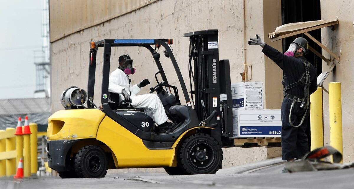 Workers wearing breathing apparatus move boxes at the Exide plant in Vernon.
