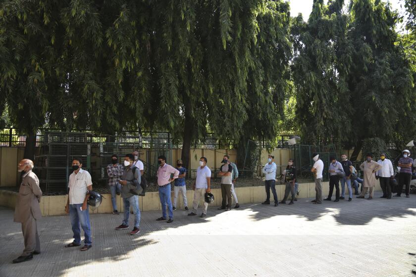 Indians wearing face masks wait for COVID-19 test report in Jammu, India, Monday, Oct.5, 2020. India, the second worst-affected nation in the world after the United States, is witnessing a sustained decline in new coronavirus infections and active virus cases have remained below the million mark for 14 consecutive days. (AP Photo/Channi Anand)