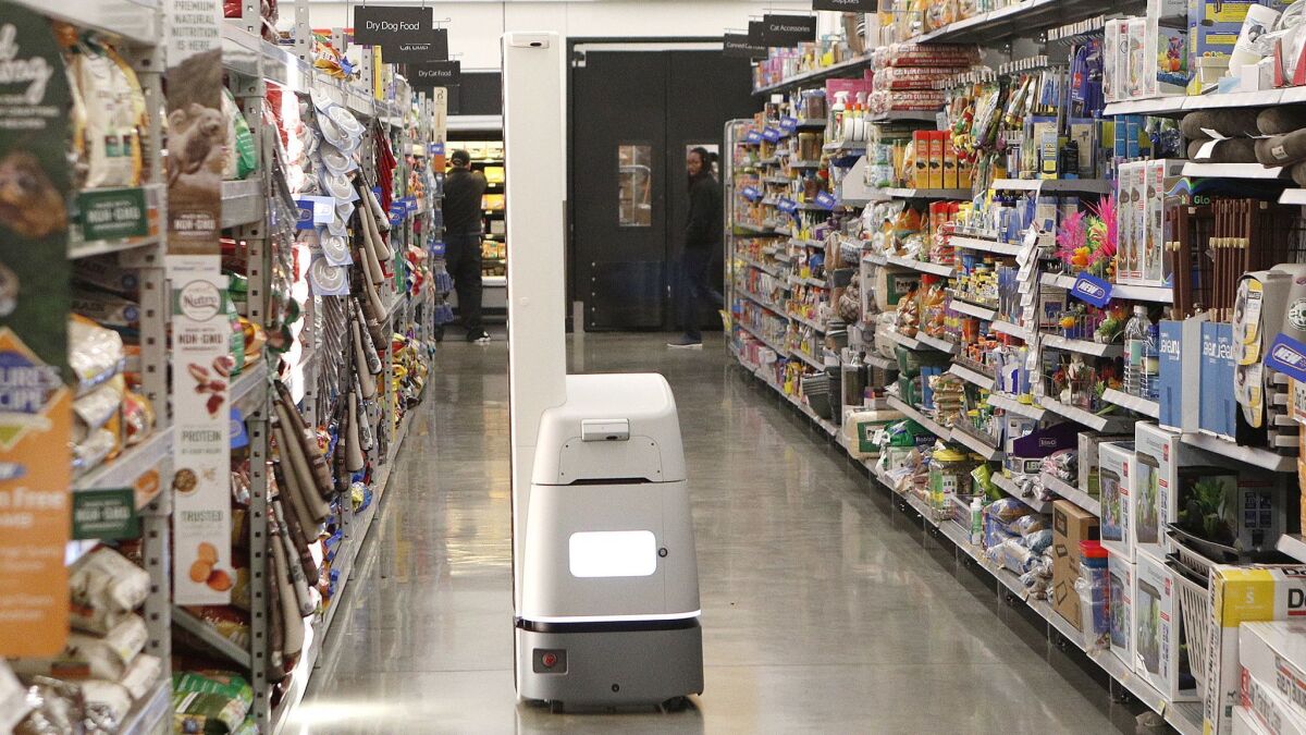 A new Bossa Nova robot rolls down an aisle at Walmart in Burbank on Wednesday. The robot, with technology similar to self-driving cars to prevent it from bumping into anything, moves up and down store aisles scanning shelves for inventory that needs restocking.