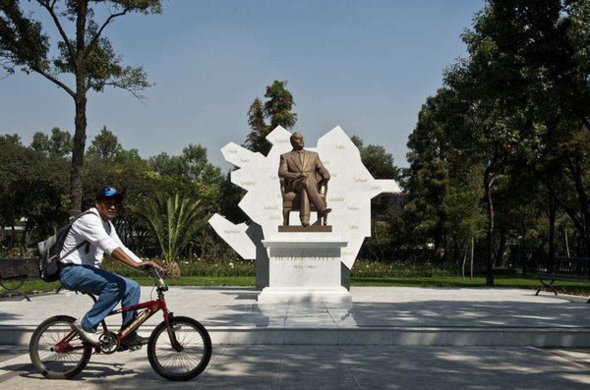 A man rides a bike in Mexico City in front of a sculpture of Heydar Aliyev, former president of Azerbaijan.