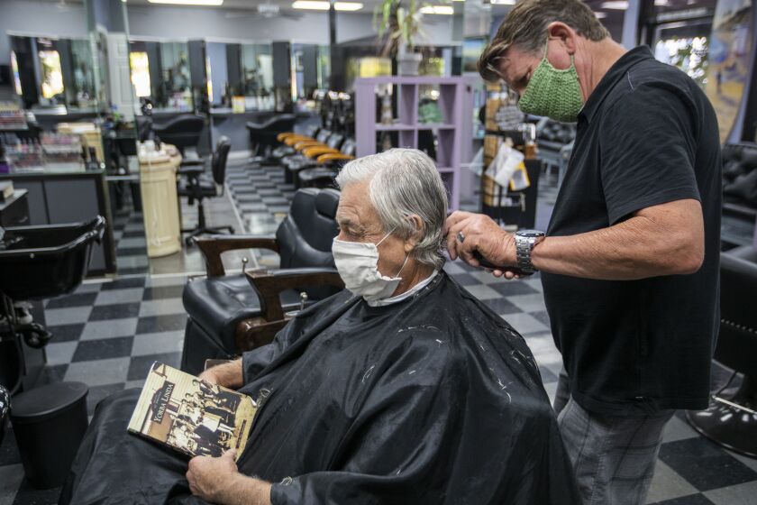 YORA LINDA, CA - MAY 26: Barber and salon owner Steve Curtis cuts Bill Janeway's hair, who was getting his first haircut since mid-February, after Gov. Newsom announced California moved into Phase 3 of reopening with hair salons, barbershops opening up, at Joncolby's Hair Salon Tuesday, May 26, 2020 in Yorba Linda, CA. Curtis said he looks forward to his customers returning and 10 independent beauticians returning to work at his salon. (Allen J. Schaben / Los Angeles Times)