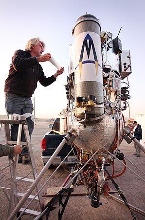 Dave Masten, owner of Masten Space Systems, attaches some last-minute tape to his rocket before heading to the launch pad at Mojave Air and Space Port on Wednesday morning. That day, his team had two unsuccessful attempts at a launch.