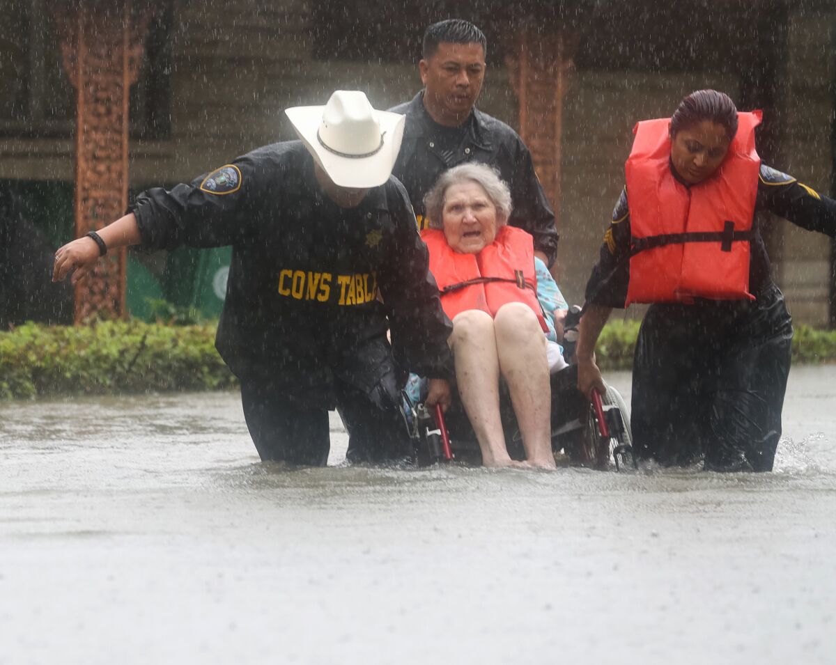 Deputy Constables Sgt. Paul Fernandez, from left, Sgt. Michael Tran and Sgt. Radha Patel rescue a woman from rising water near Brays Bayou after heavy rains on Sunday.