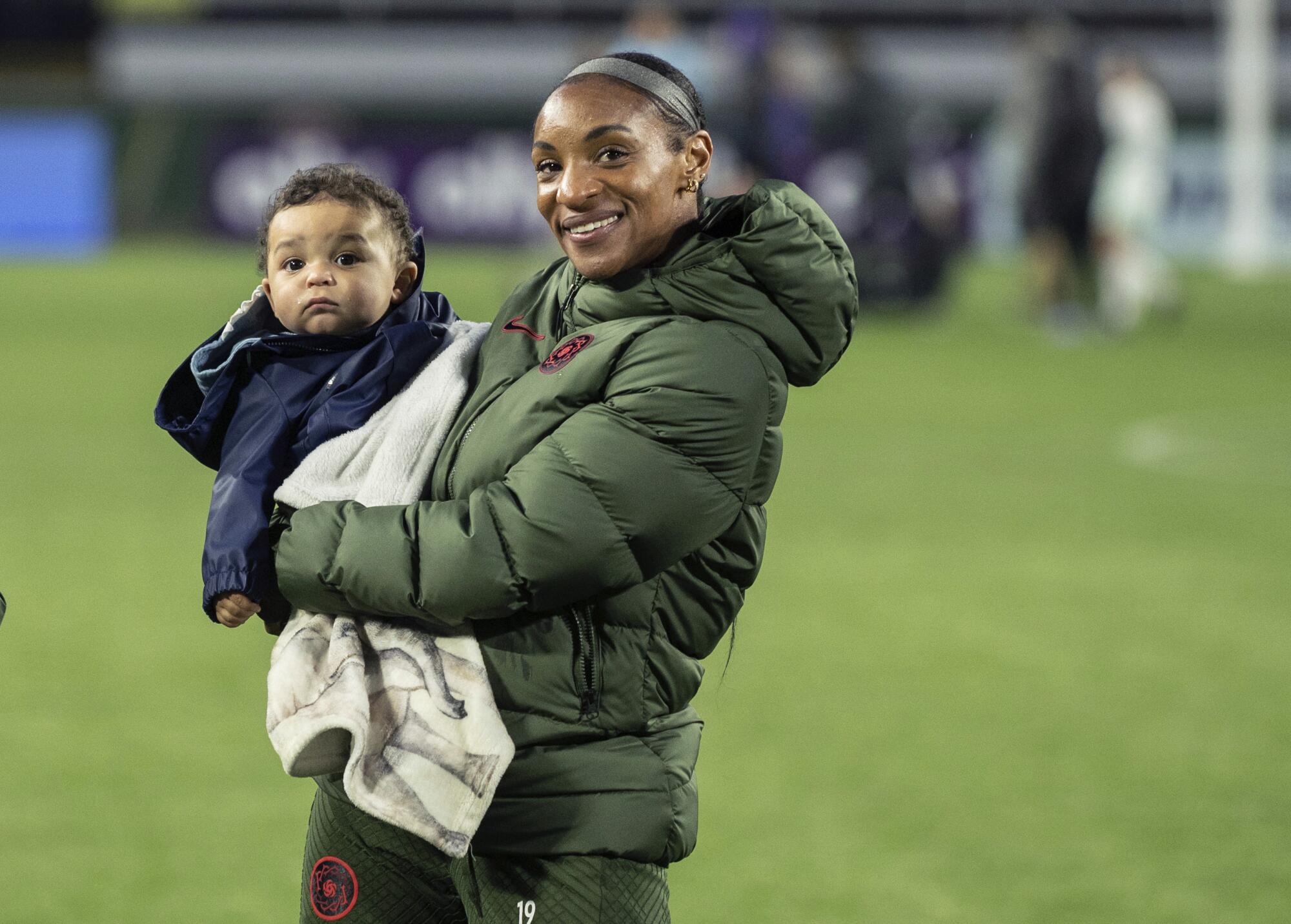 Crystal Dunn holds son Marcel after a preseason NWSL game in Portland.