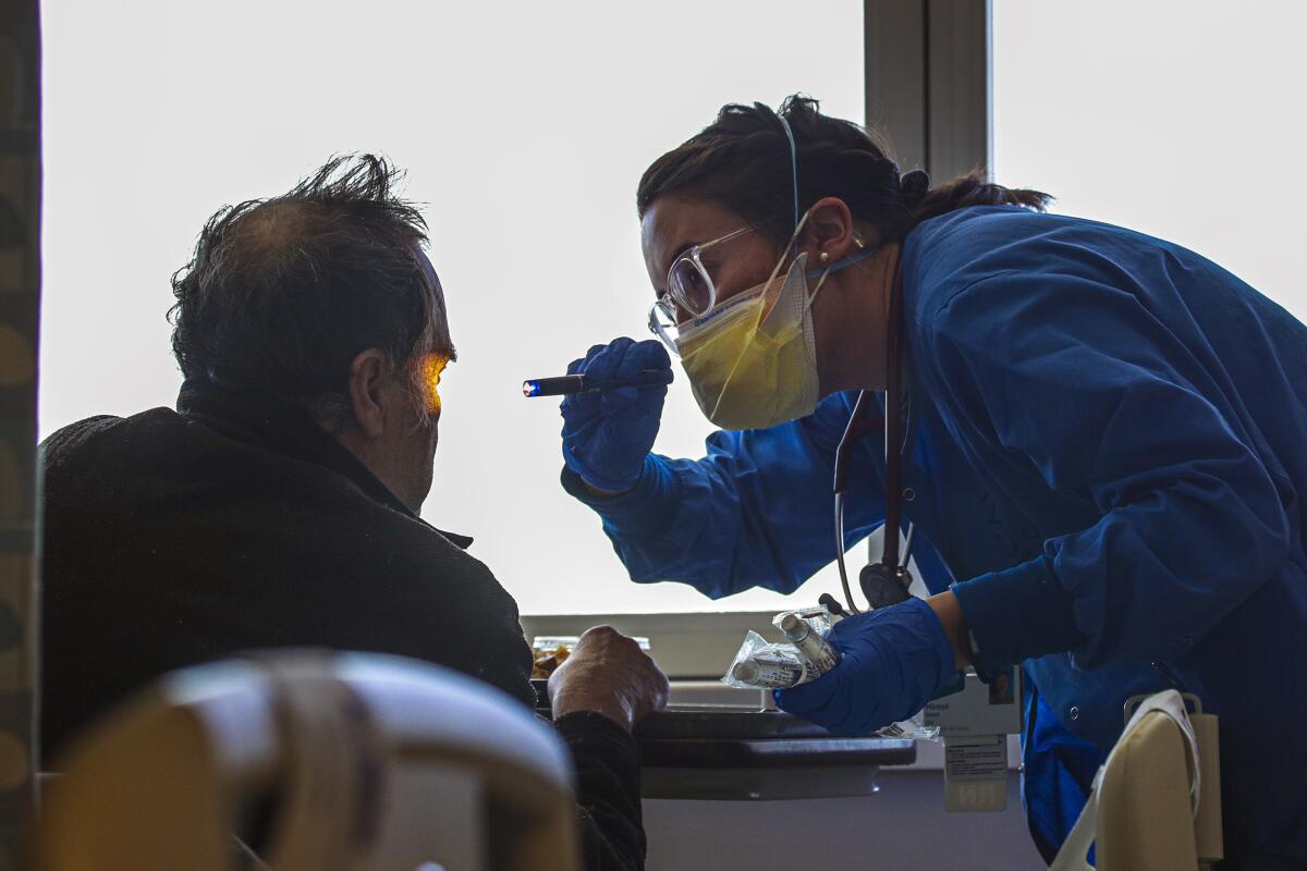 A nurse uses a flashlight to look into a patient's eyes