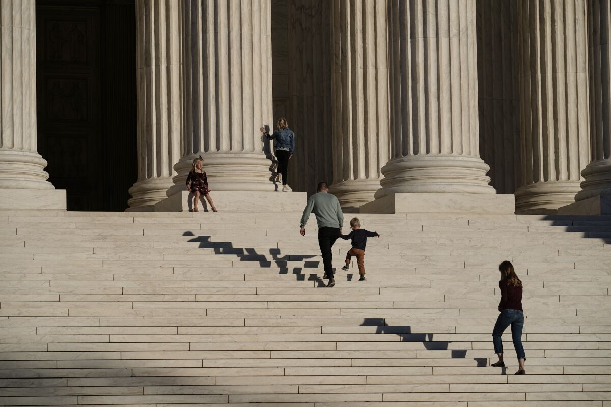 A family visits the Supreme Court in Washington, Wednesday, Nov. 4, 2020. The Trump campaign is seeking to intervene in a Pennsylvania case at the Supreme Court that deals with whether ballots received up to three days after the election can be counted. (AP Photo/J. Scott Applewhite)