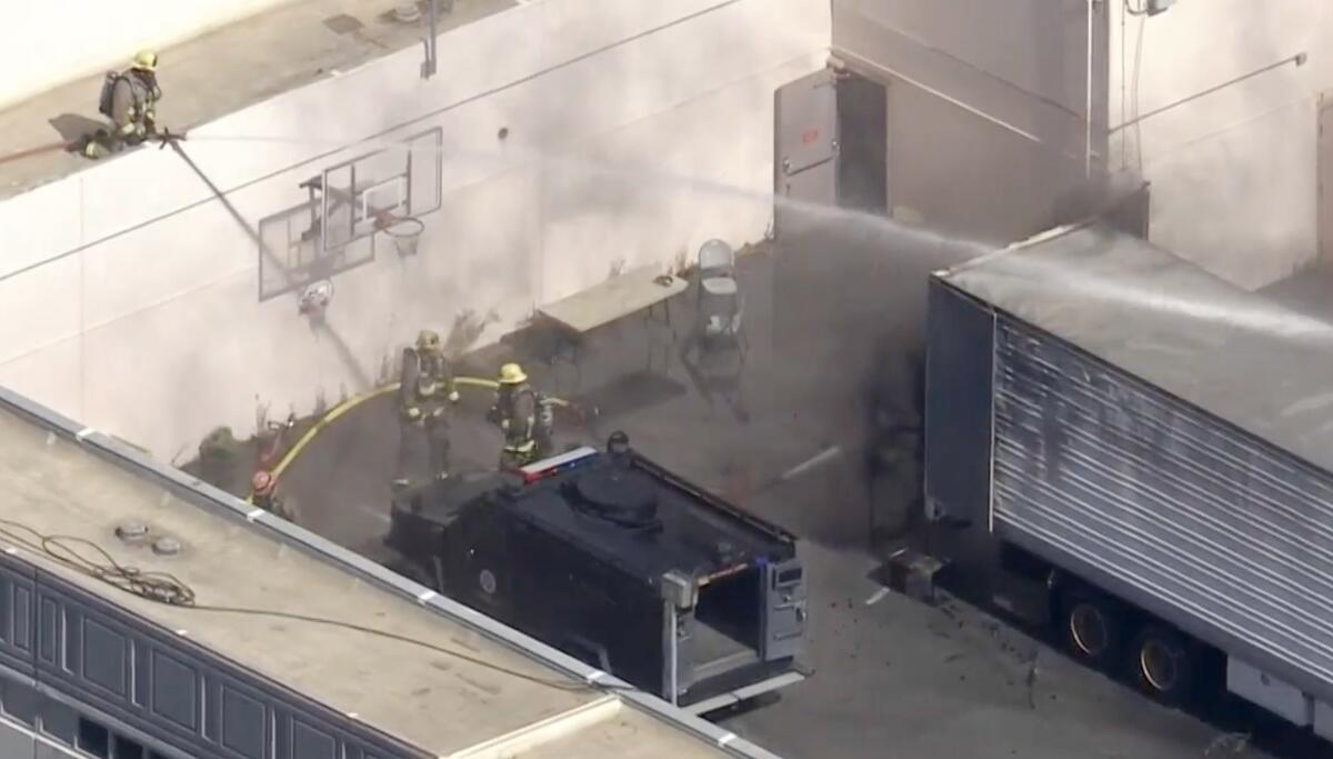 Aerial view of fire workers and water being sprayed near a trailer