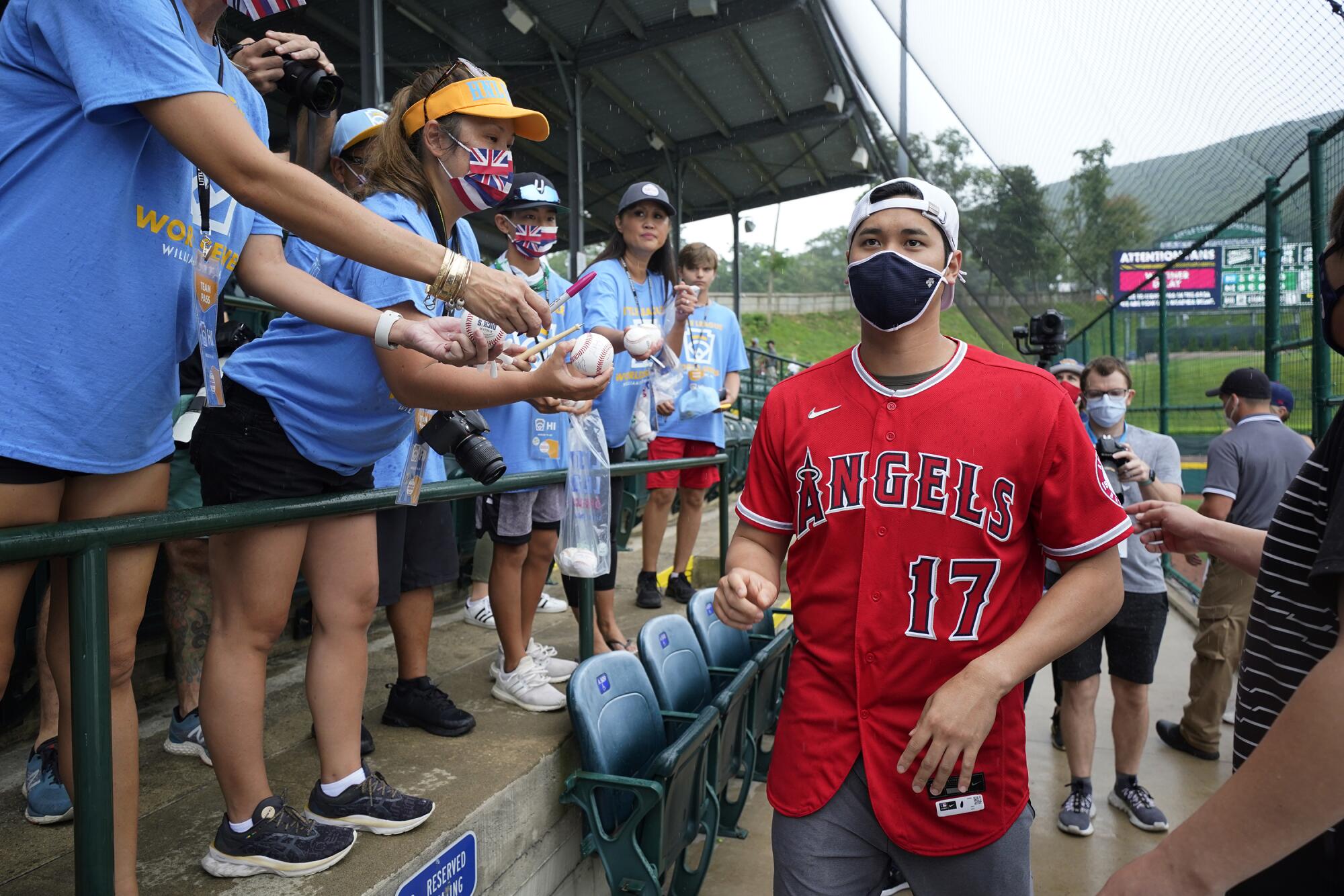Los Angeles Angels' Shohei Ohtani gives autographs to parents of the Honolulu, Hawaii, Little League
