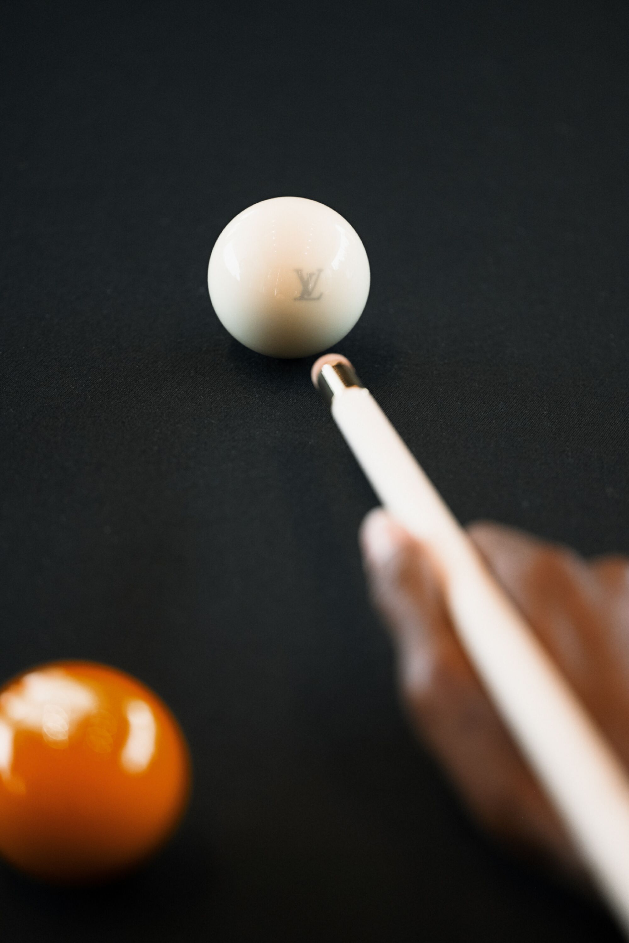 A pool cue aims at a white billiards ball.