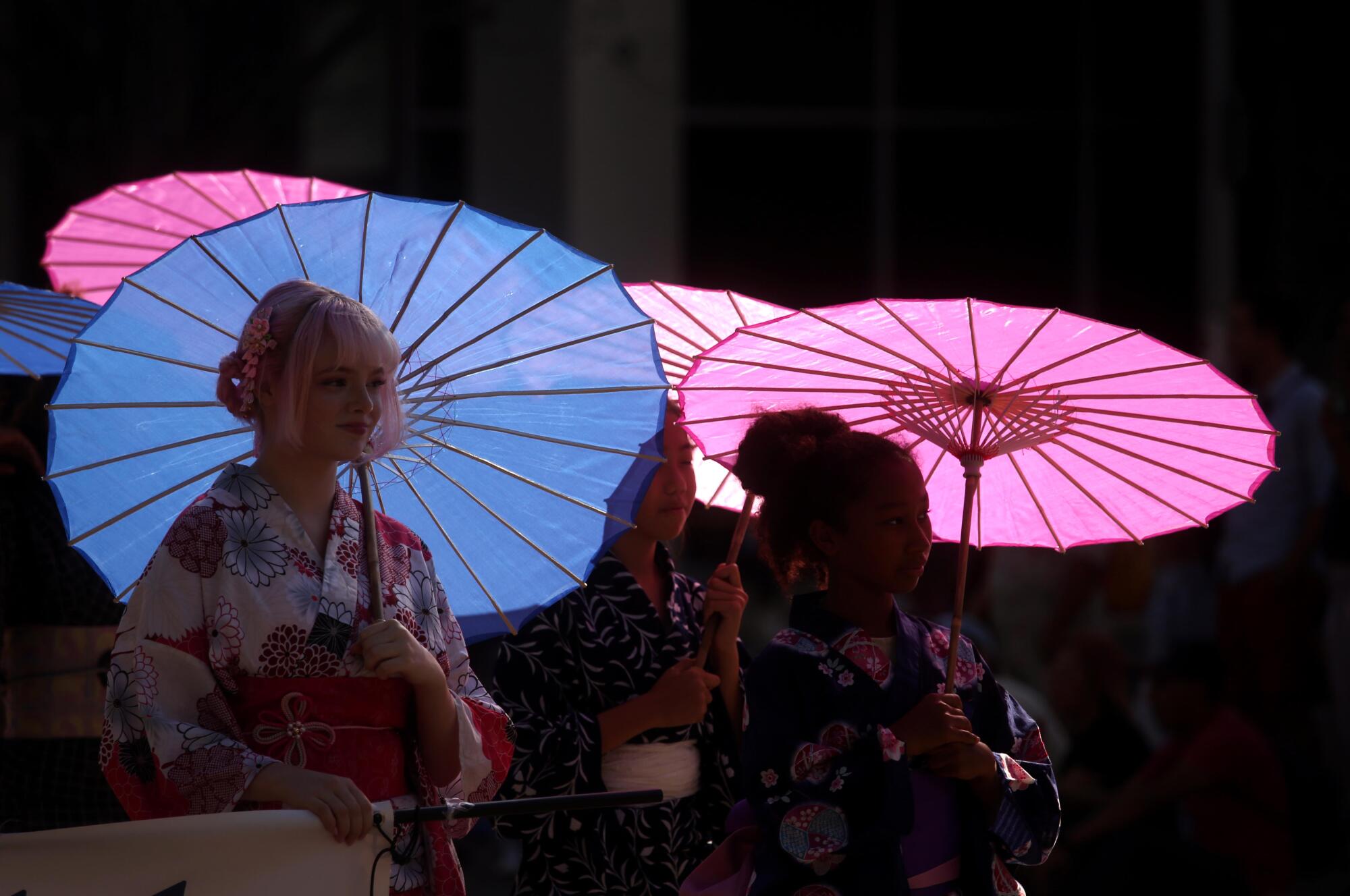 Members of the Kimono Club hold pink and blue parasols.