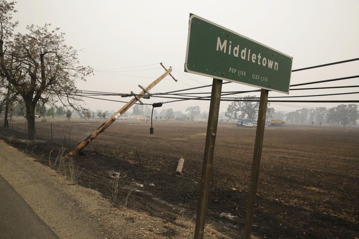 A downed power pole continues to burn along Highway 29 on Sunday in Middletown, Calif.