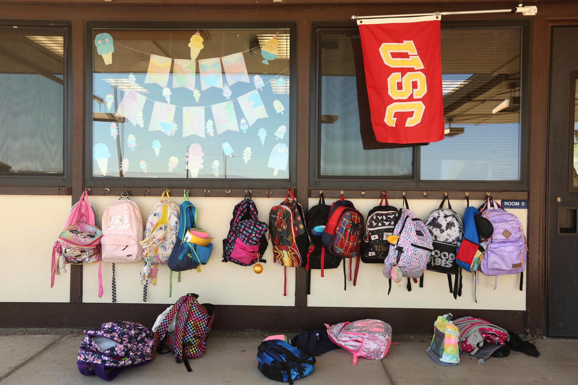 Backpacks are left hanging next to a USC banner outside a classroom at Alturas Elementary School. 