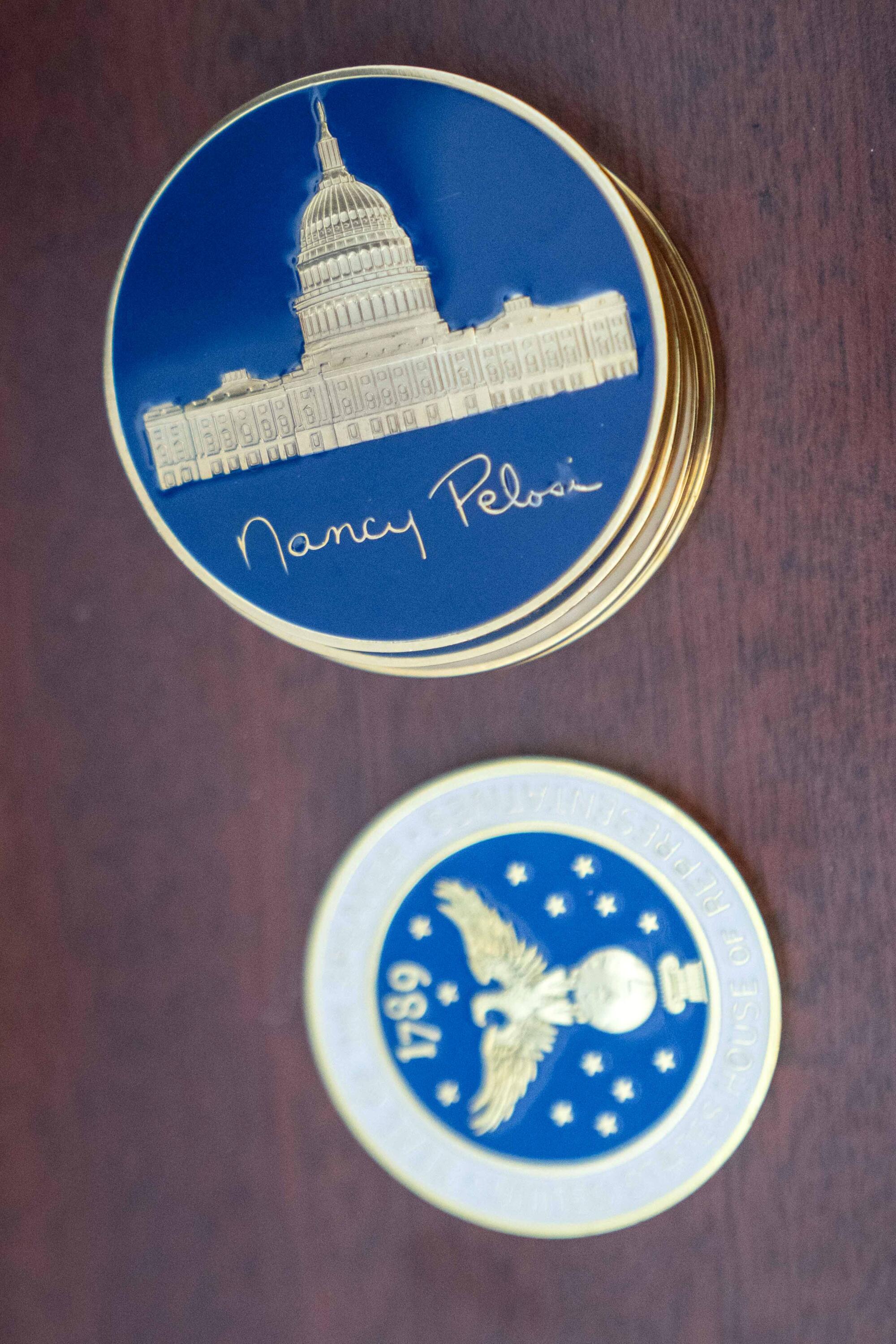 Challenge coins with Nancy Pelosi's signature displayed on a desk in her office in the Capitol.