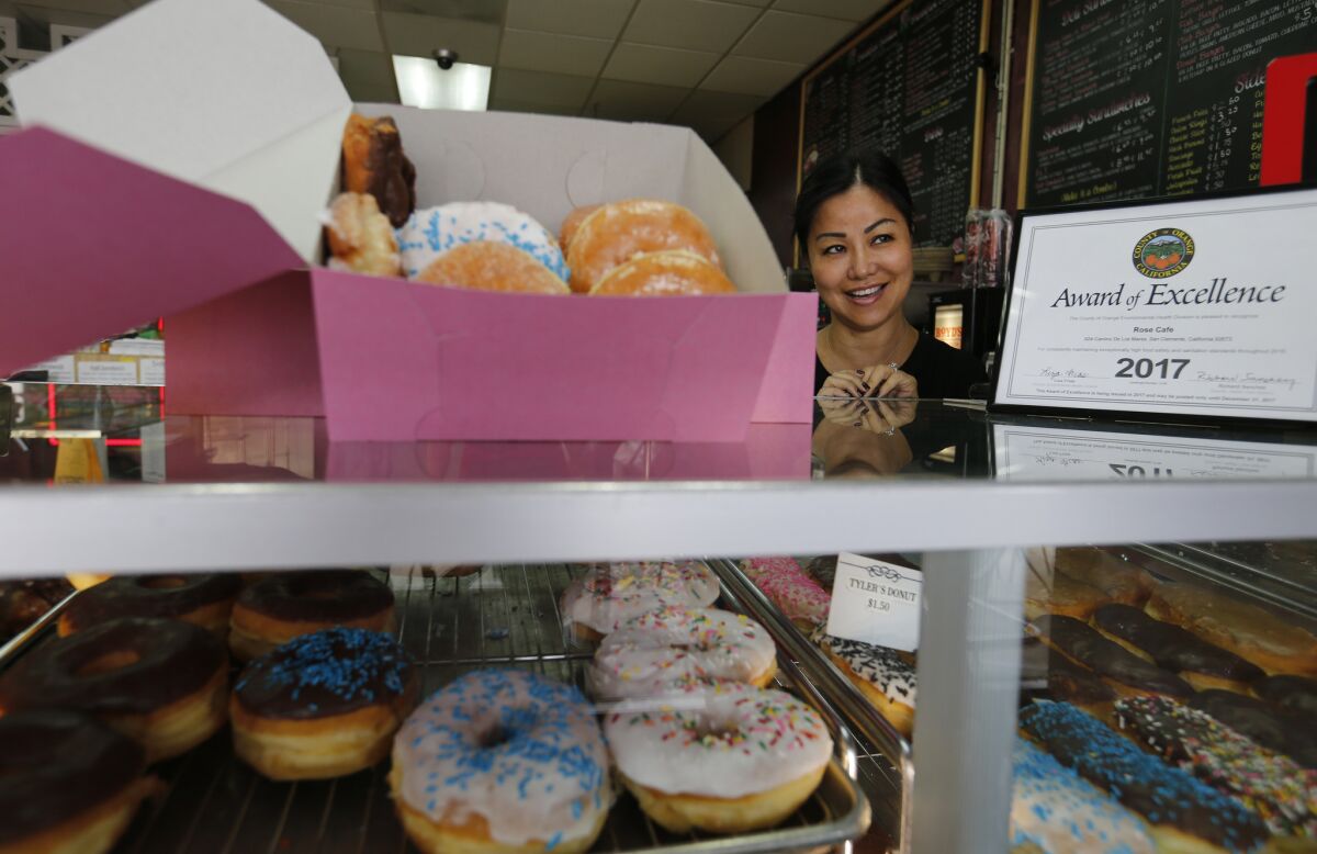 Susan Lim, a Cambodian-American-owner of Rose Donuts & Cafe, serves doughnuts at her San Clemente store.