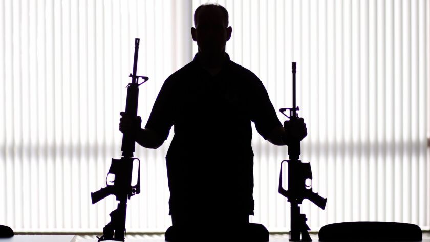An ATF agent poses with homemade rifles at an ATF field office in Glendale, Calif. on Aug. 29.