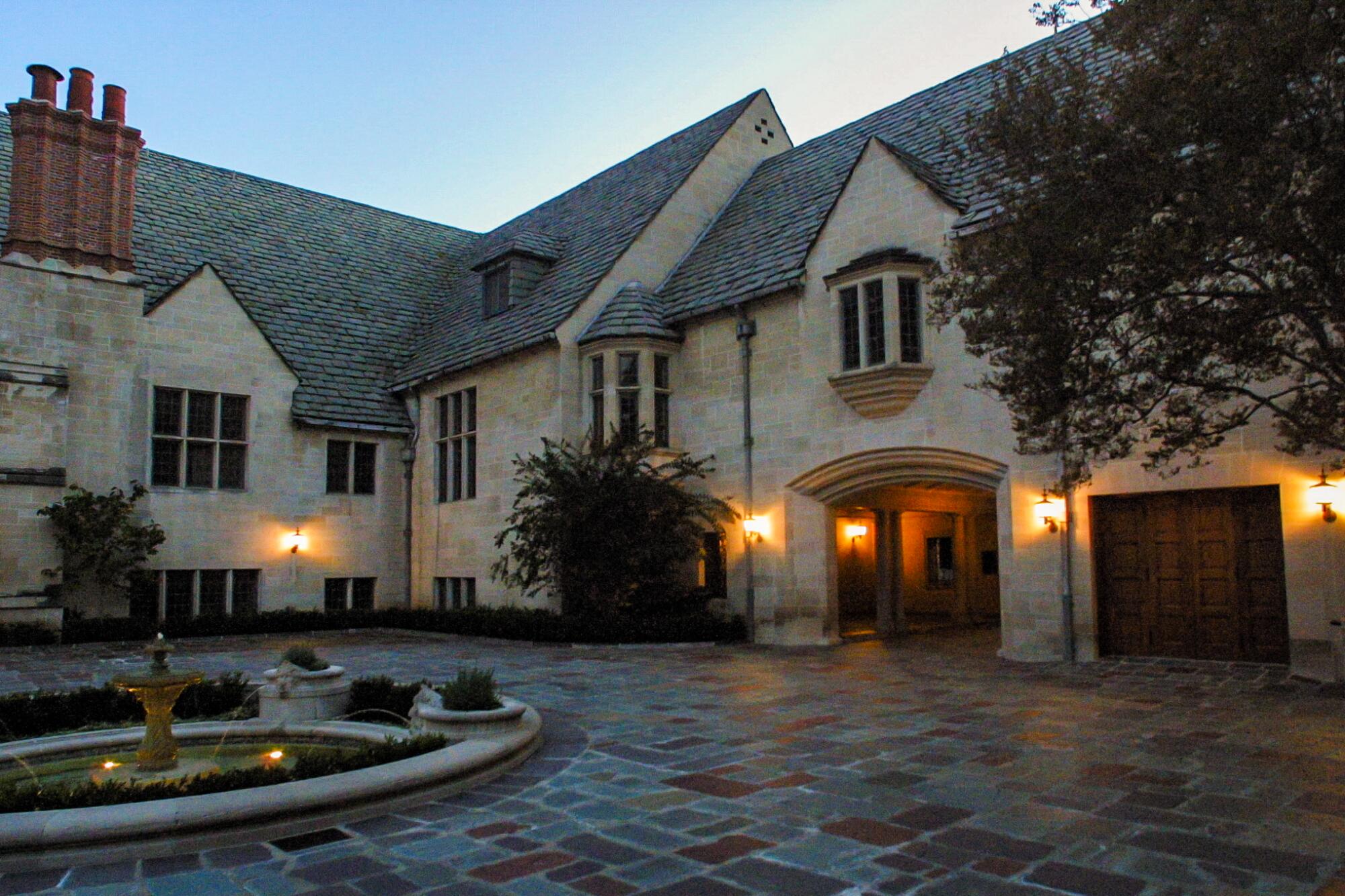 Porte cochere at Greystone Mansion at twilight, with lights on the building glowing