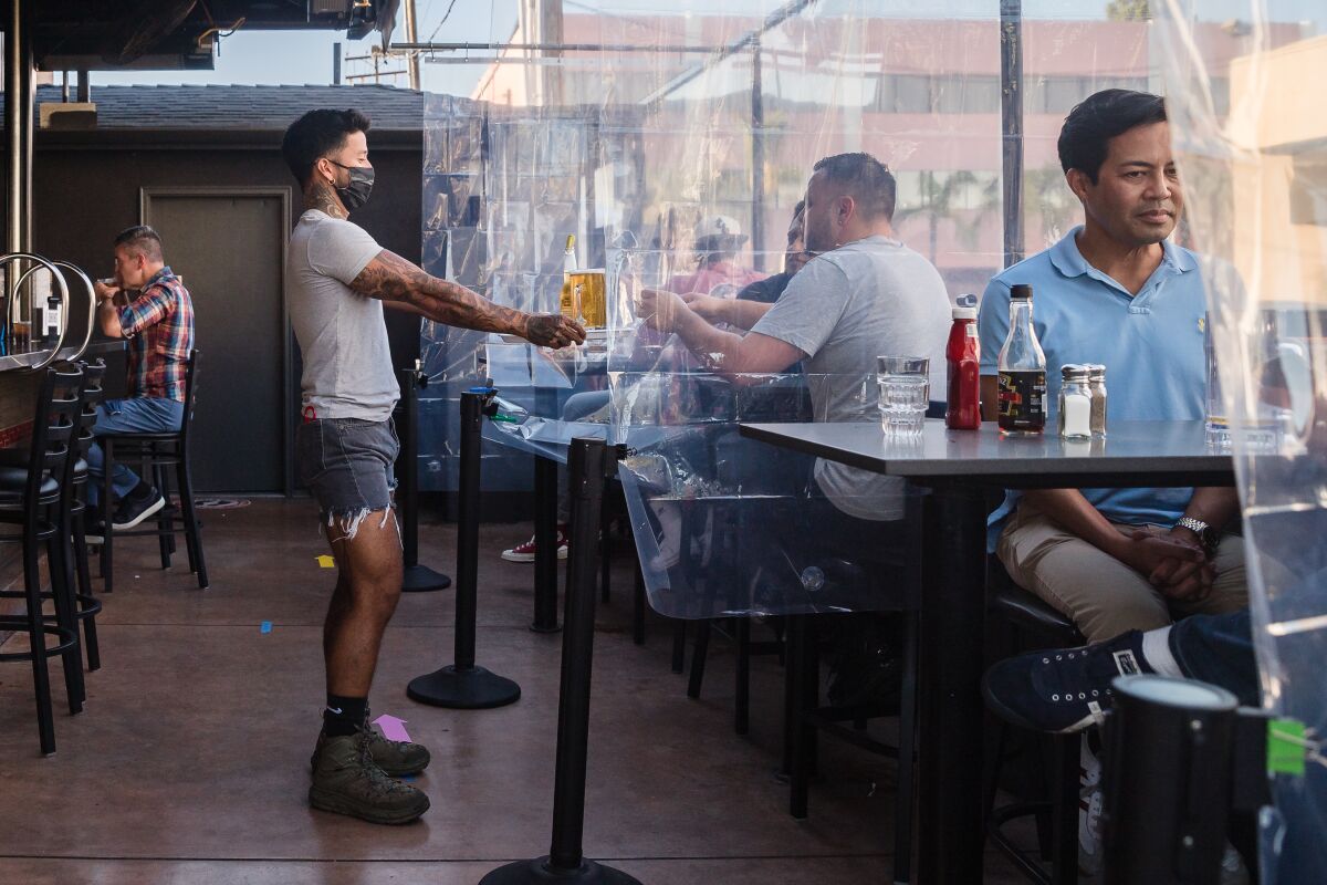 Customers sit at tables divided with clear plastic shower curtains at Urban MO's Bar & Grill on July 2, 2020 in Hillcrest