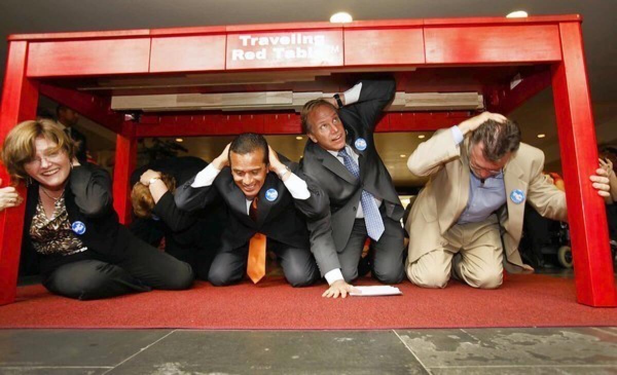 From left, Lucile Jones, Mayor Antonio Villaraigosa, Paul Schulz of the American Red Cross and MTA official Richard Katz drop under a table during the earthquake drill.