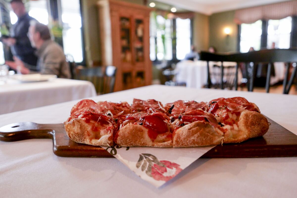 A close-up of a pizza slice sitting on a table at Nella Kitchen and Bar.