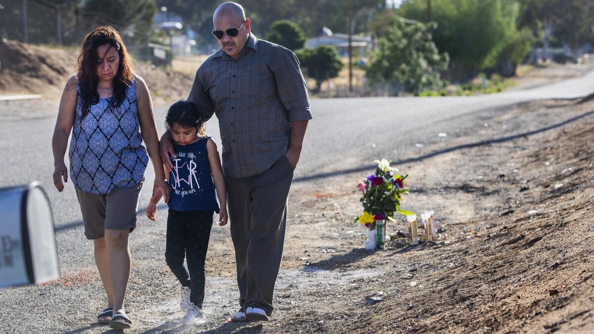 Carlos Garibay, his daughter Melanie and wife Penny Garibay walk close together after dropping off a bouquet of flowers at the scene where two boys were killed Tuesday in an alleged street racing incident. Melanie Garibay was a classmate of one of the boys.