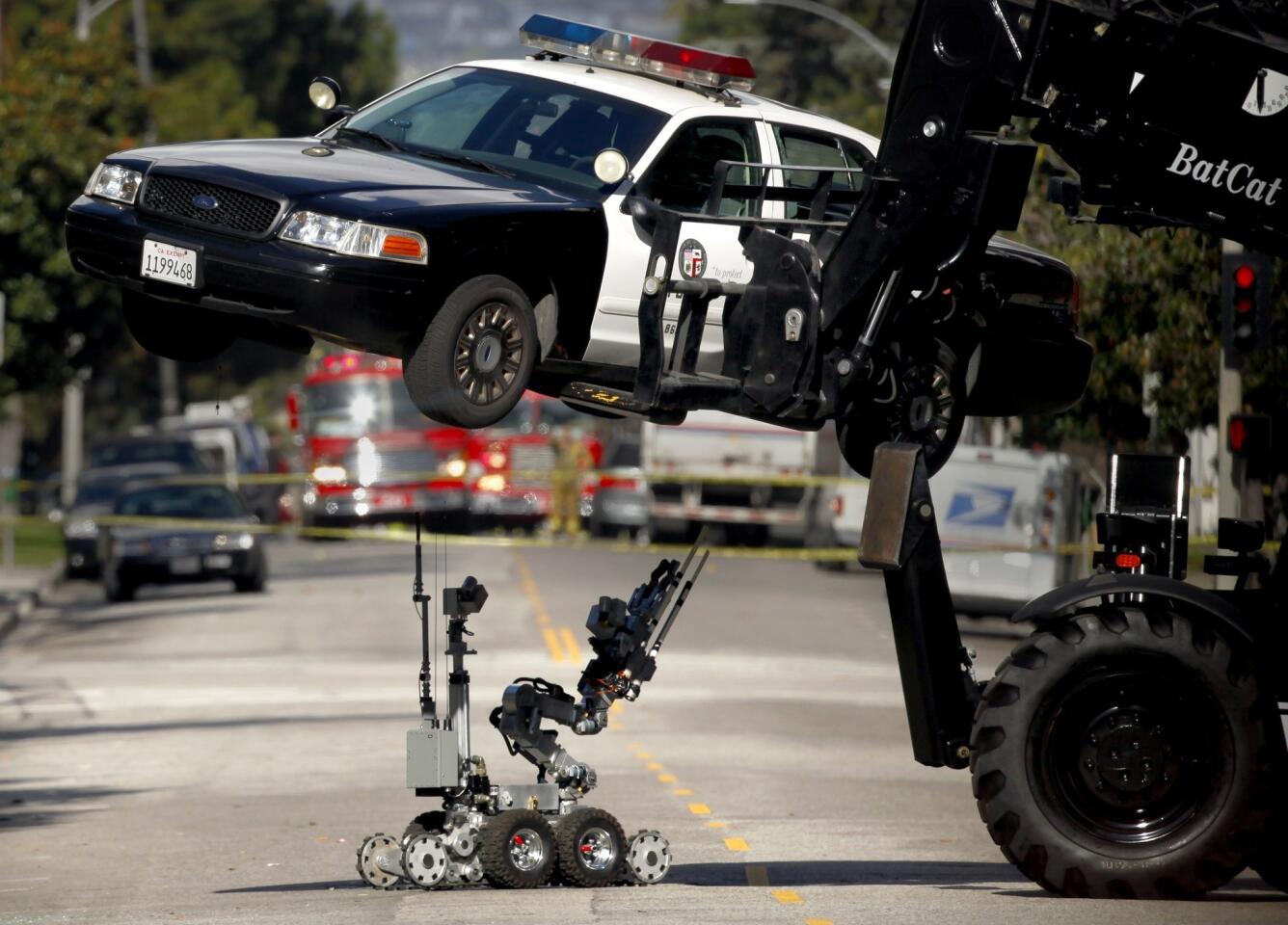Los Angeles Police Department bomb squad members take a closer look at the underside of an LAPD patrol car with a robotic device after authorities received a call that a bomb had been planted in the vehicle on Harvard Boulevard near Wilshire Boulevard.