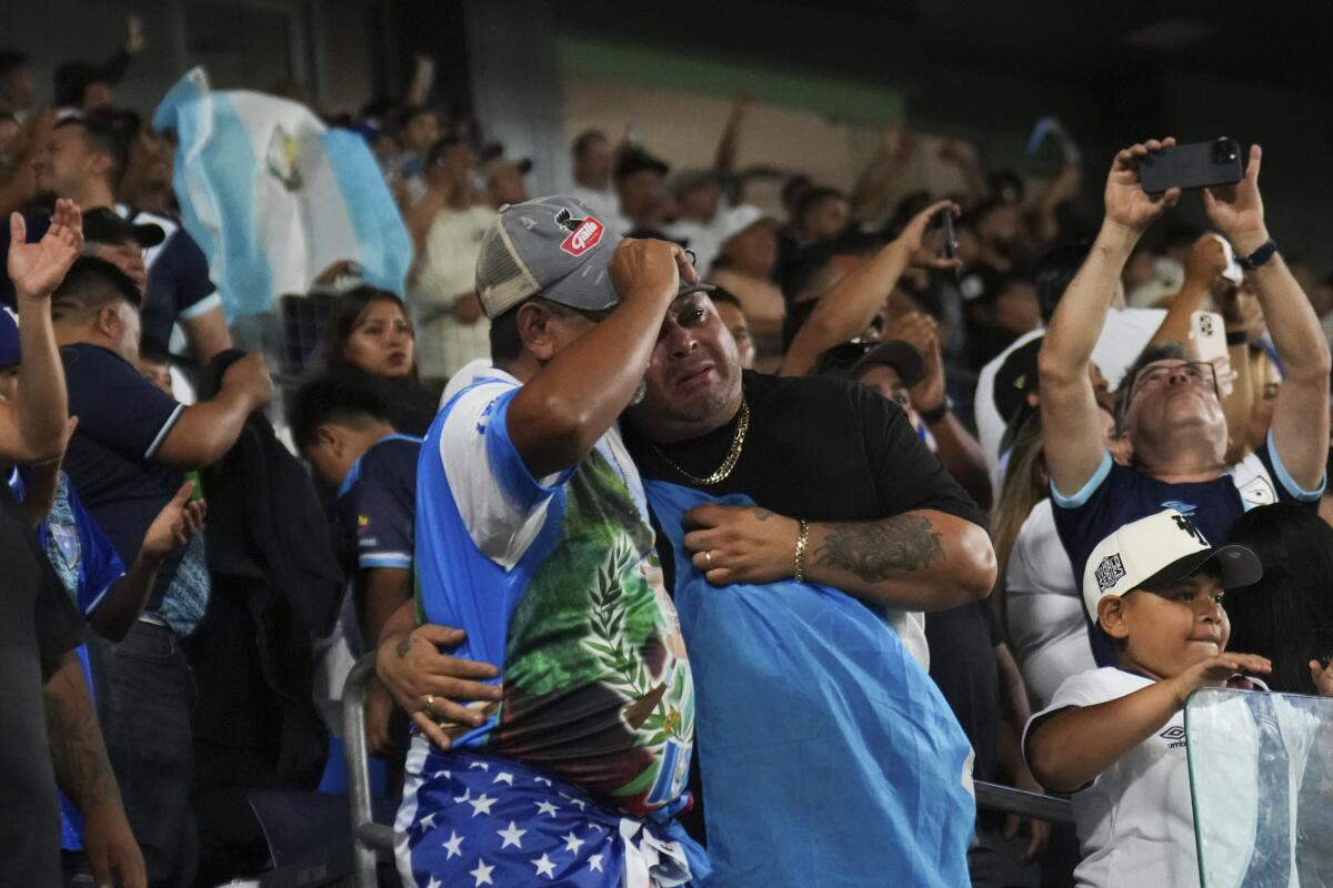 Two Guatemala fans embrace each other while cel ng)