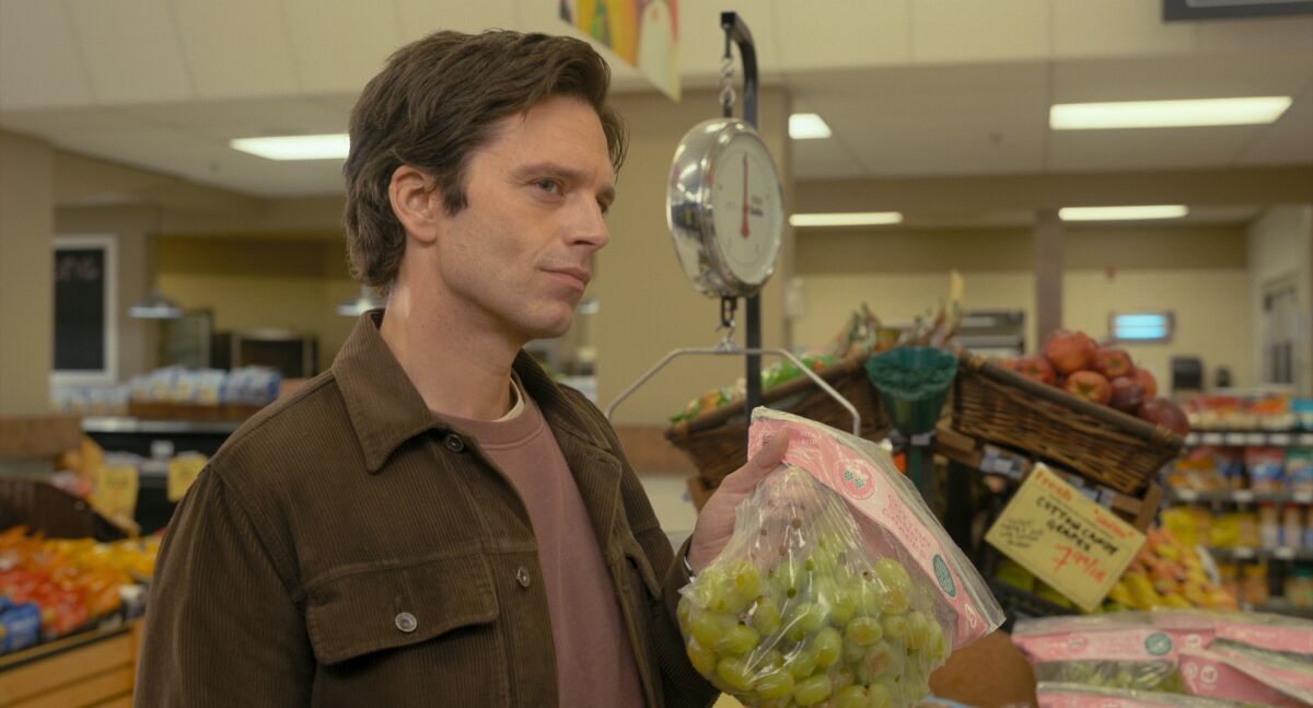 A man in a grocery store holding a bag of grapes.