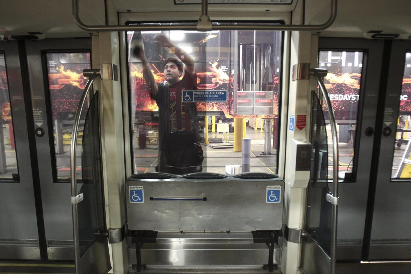 Viewed from inside a trolley car, David Garcia puts perforated material that is transparent for the windows as he and a crew put on an advertising wrap for TBS television host Conan O'Brien's talk show.